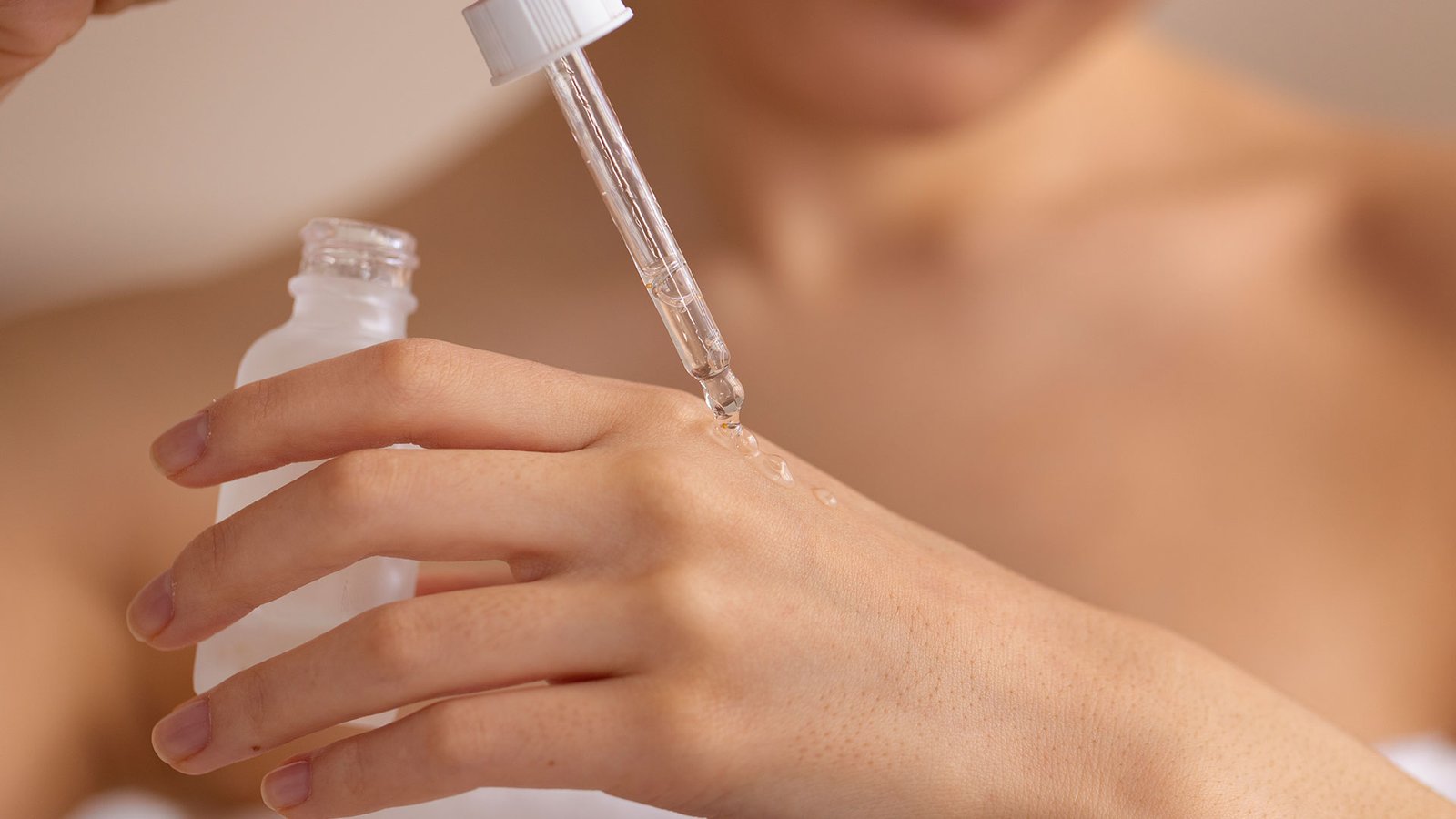 A woman applying anti-aging peptide serum onto her hand with a skincare dropper bottle